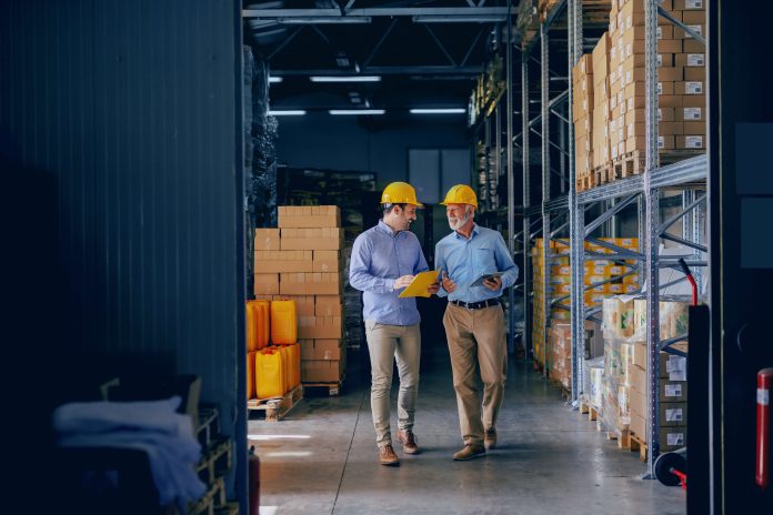 dois trabalhadores em um estoque conversando sobre processos